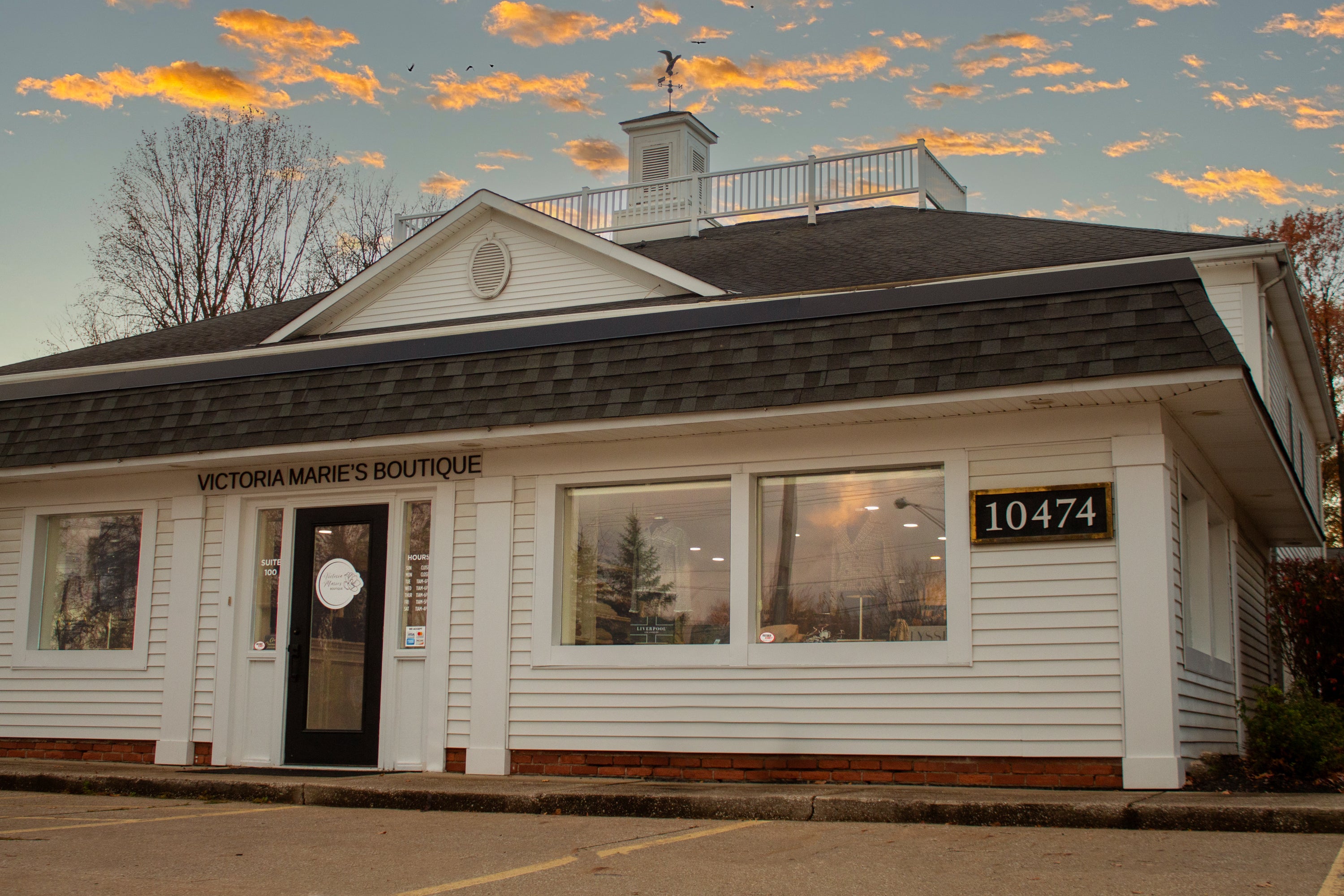 Building with 'Victoria Marie's Boutique' sign and address number 10474, during sunset.