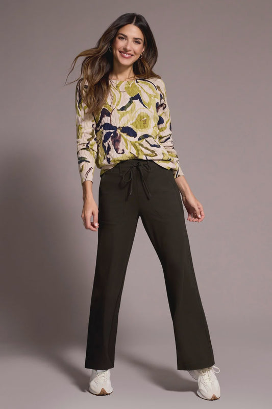 Woman wearing a floral top and black pants against a plain background