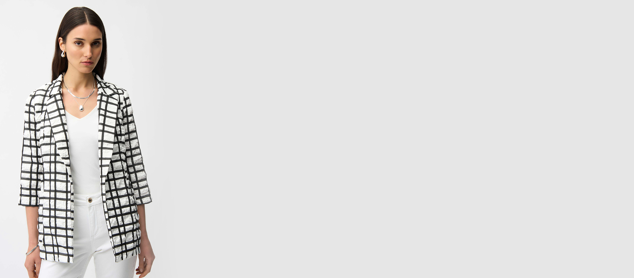 Woman wearing a black and white checkered blazer on a plain background